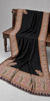 Close display of the black Kani shawl's Moonlight zari border and paisley detailing on a bench — Taj Mehal Handicrafts