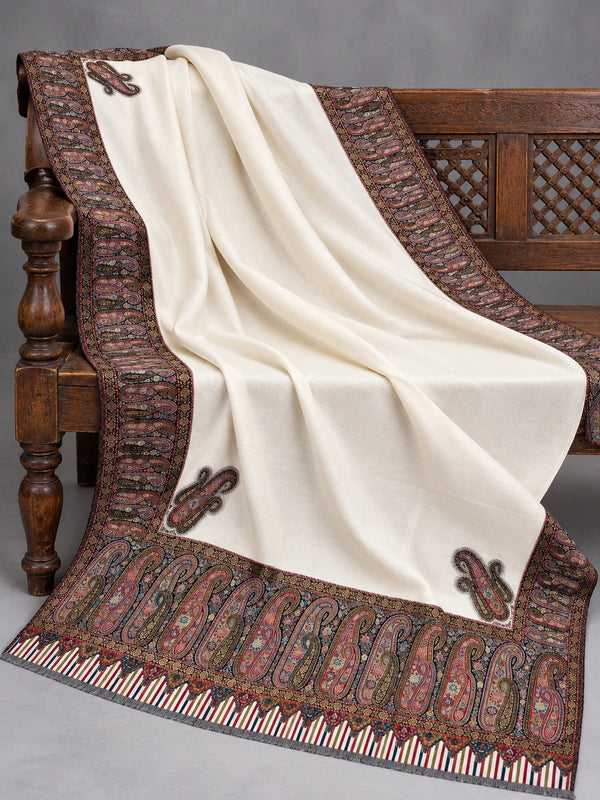 Close view of the ivory Kani shawl's multicolour paisley border and striped edge on a bench — Taj Mehal Handicrafts