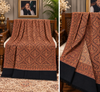 Moonlight Kani reversible Matka design women's shawl displayed on a carved wooden bench, rust brown and black pattern, Taj Mehal Handicrafts Islamabad