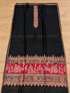 Black Moonlight Shikargah unstitched suit fabric with ornate red and multicolour border, displayed on a wooden floor – Taj Mehal Handicrafts