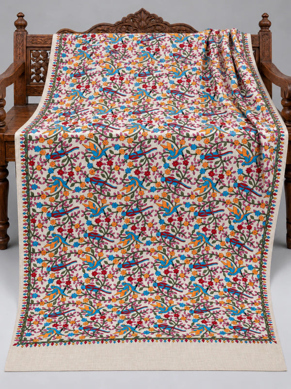 Ivory parrot embroidered shawl with colourful flowers, green vines and a plain edge without tassels, displayed on a wooden bench | Taj Mehal Handicrafts